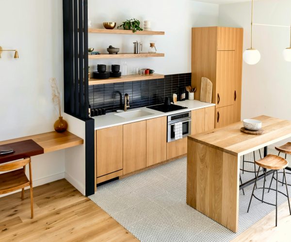 Light-filled modern kitchen interior with wooden furnishings and black accents.
