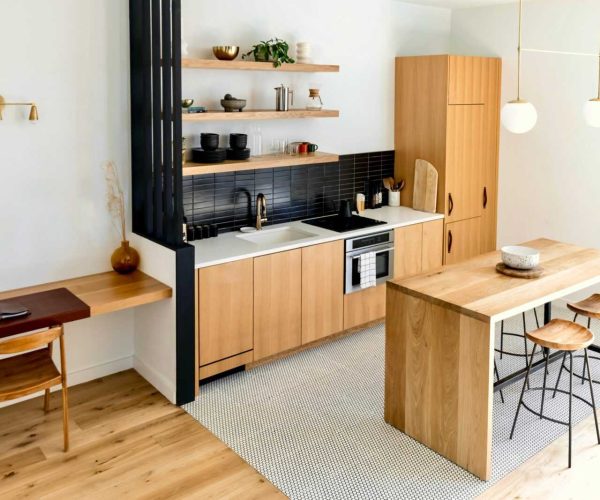 Light-filled modern kitchen interior with wooden furnishings and black accents.