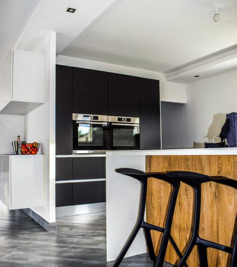 A contemporary kitchen featuring sleek cabinetry and elegant bar stools in a minimalist design.